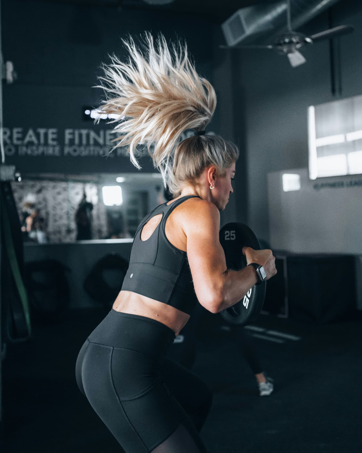 Woman training with a weight plate in a gym